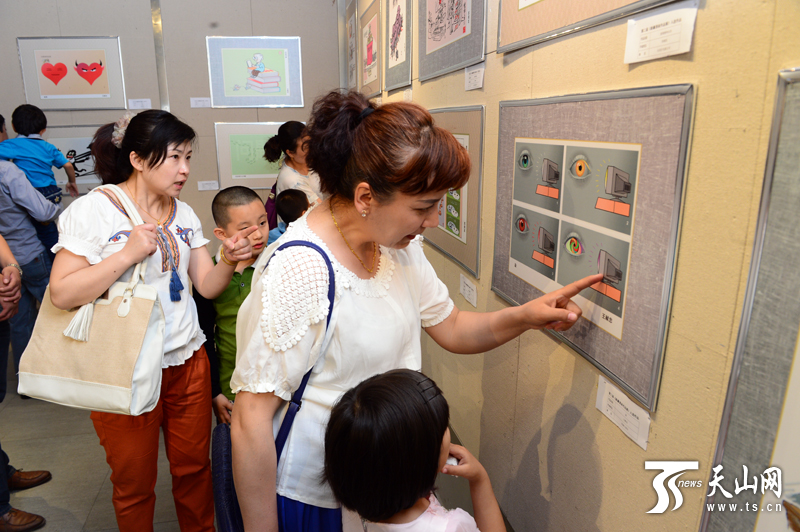 “新疆新闻漫画作品展”在乌鲁木齐文化馆开展,市民参观展览。